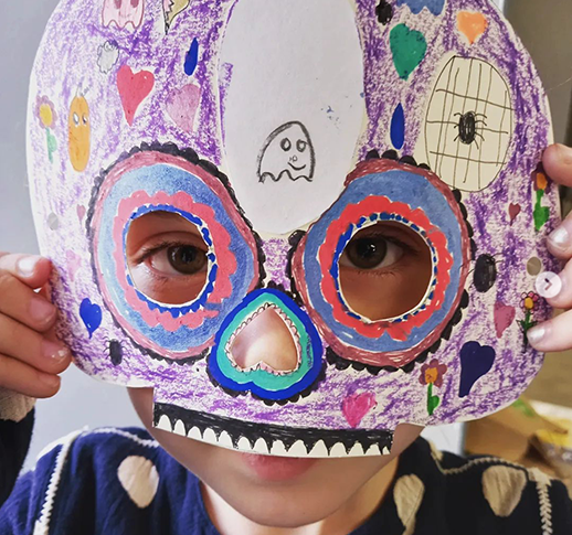 Photo du visage d'un enfant portant un masque mexicain réalisé en papier et colorié
