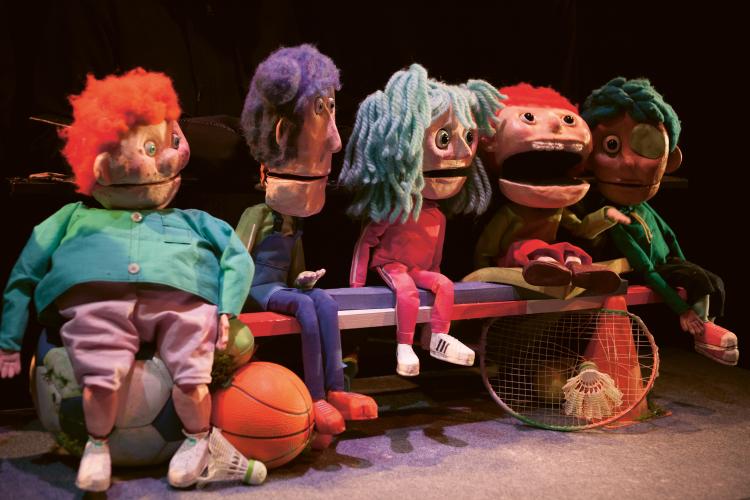 PHoto de cinq marionnettes assissent sur un banc de bois