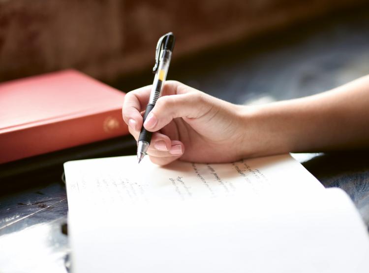 Photo d'une main en train d'écrire dans un cahier